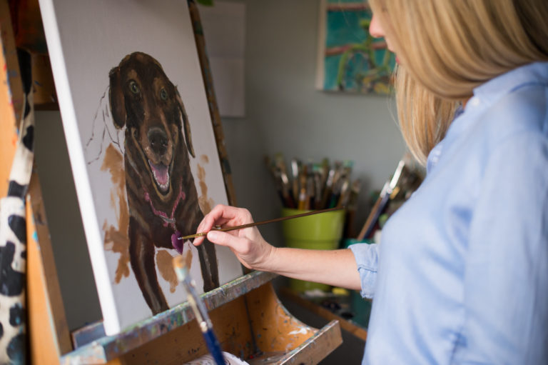 Sarah Lytle actively painting a chocolate lab. 