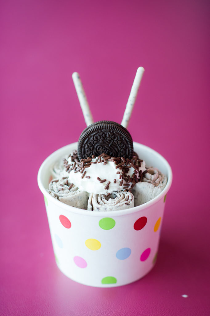 A rolled ice cream with Oreos and sprinkles. 
