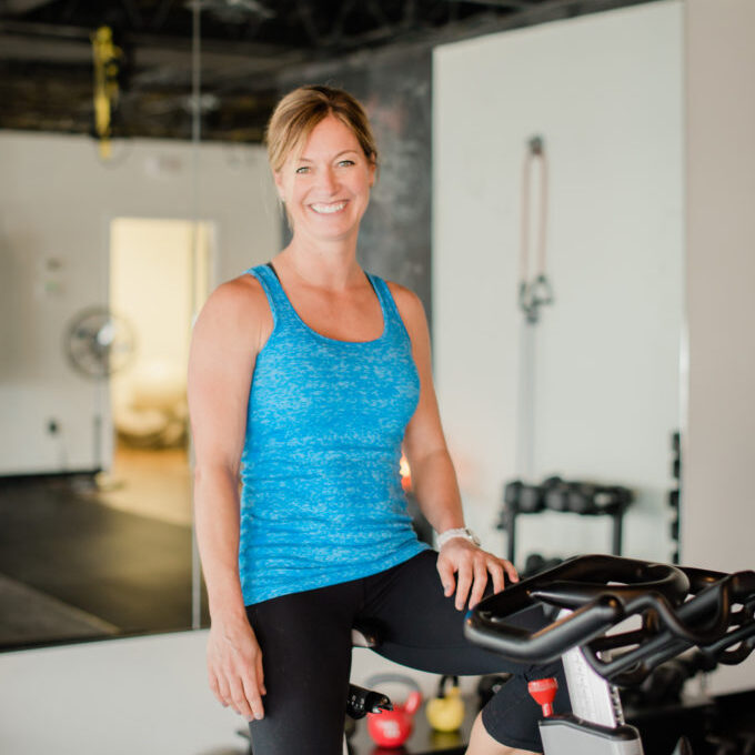 Feature image of FIT HUB’s owner Lori Teppara sitting on a bike.