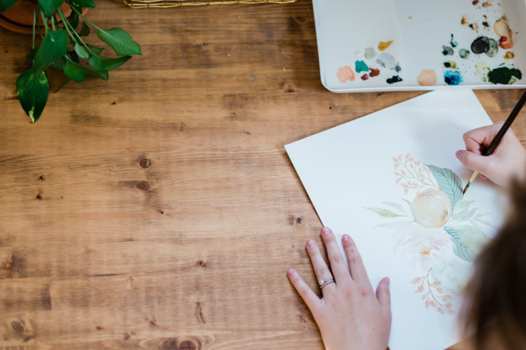 Taylor Mahlke paints a water color portrait of flowers for a new product at Pen + Pillar. 