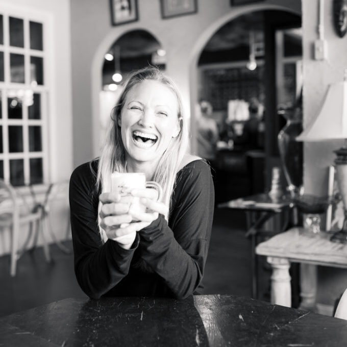 Feature image of Debeen owner Debbie Maier laughing and holding a cup of coffee in her High Point, NC coffee shop