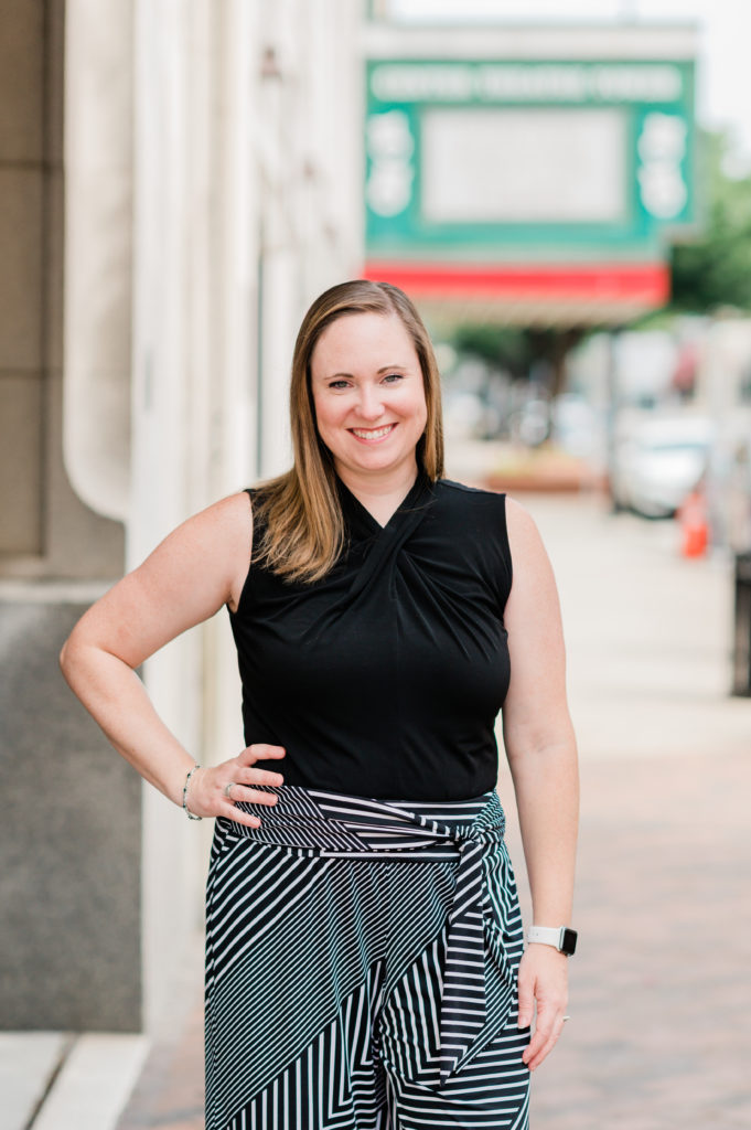 Ashley D. Grigg, Director of Marketing and Communications for the High Point Market Authority puts one arm on her hip and poses for a photo. 