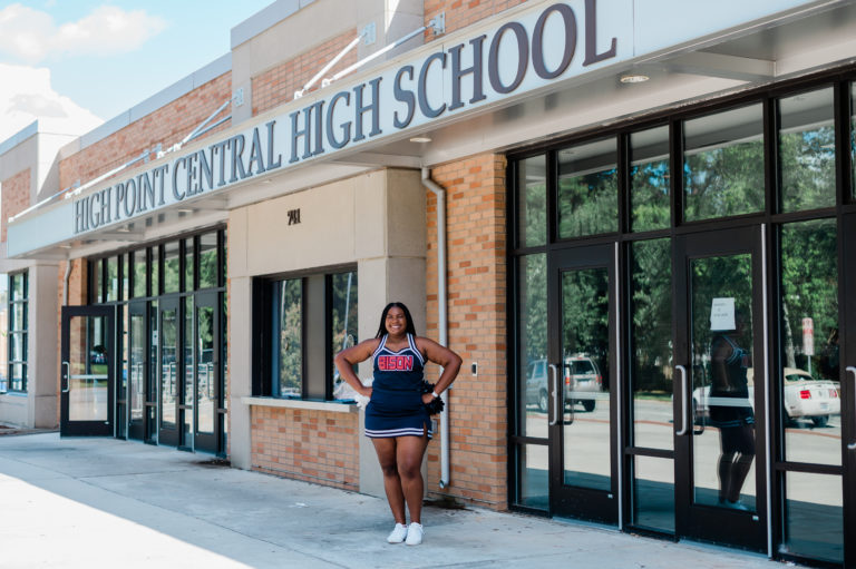 Outstanding Student Camryn Torrence stands outside of High Point Central High School in her cheerleading uniform 