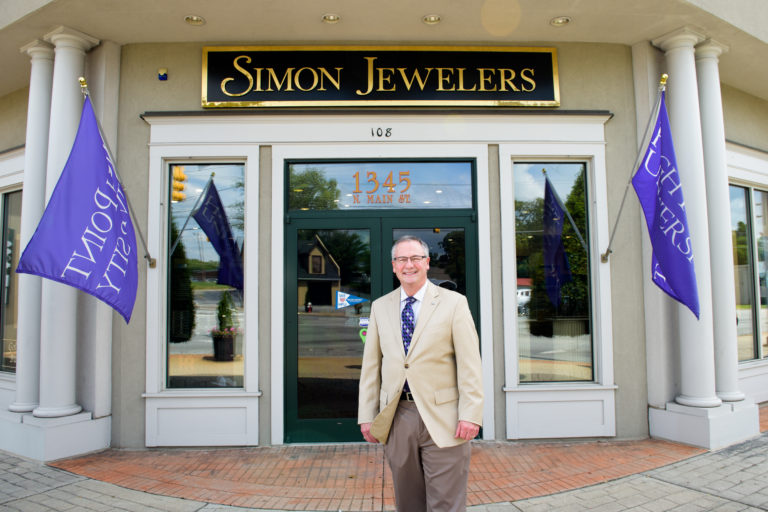 The owner of Simon Jewelers stands outside of his store on main street 