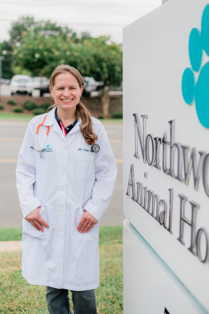 Dr. Rebecca 'Reba' Slivka stands next to teh Northwood Animal Hospital sign. 