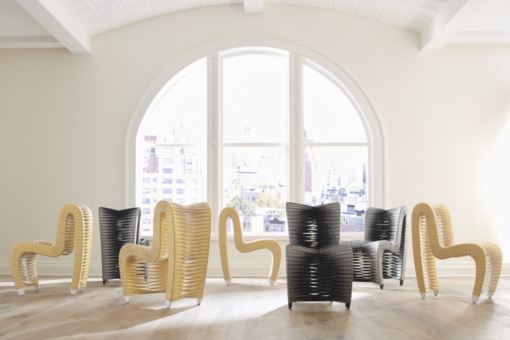 A showroom floor with 6 modern chairs sitting in front of an arched glass window.
