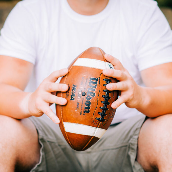 A man in a white t-shirt holds a football in High Point, NC