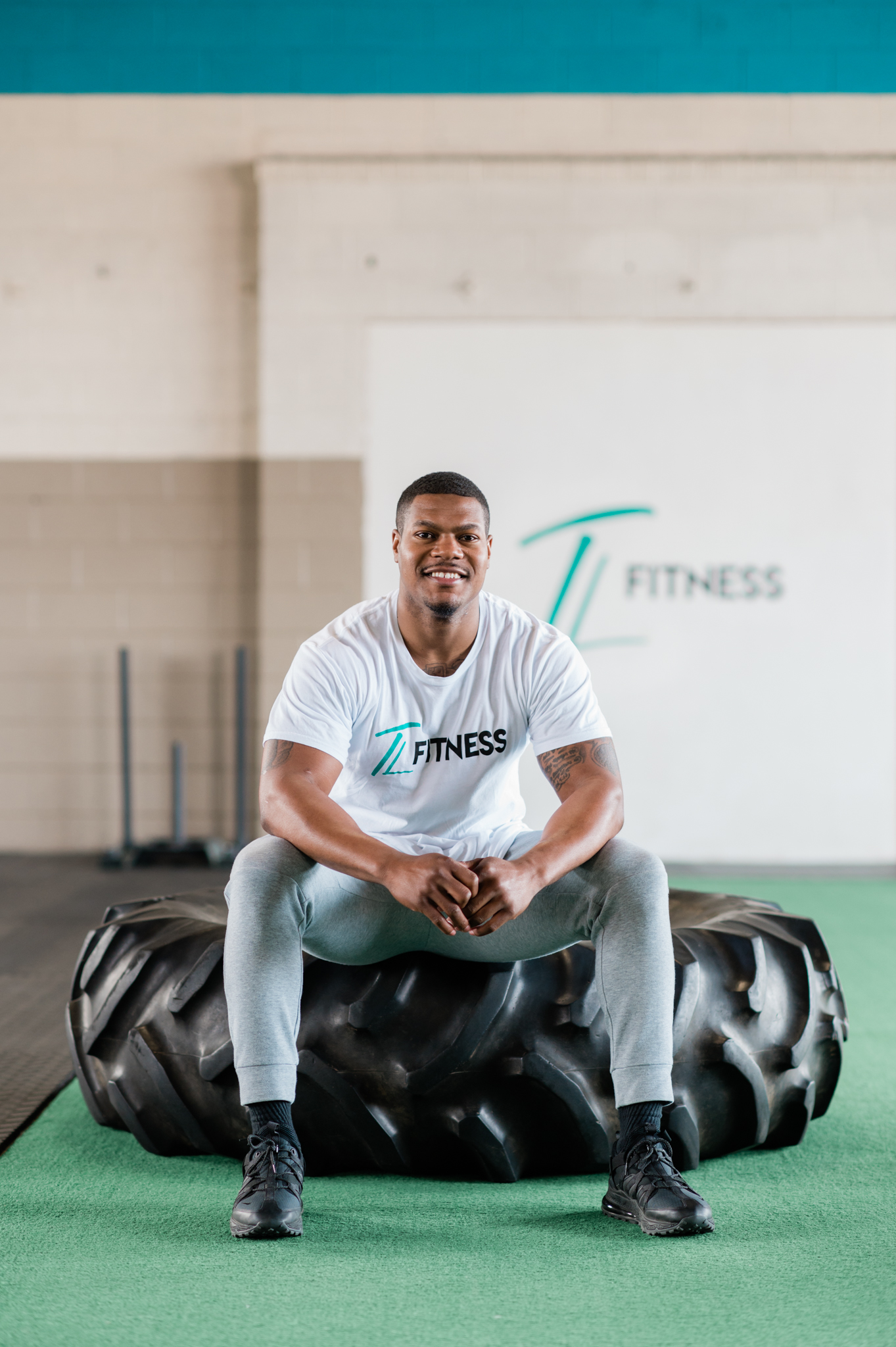 Torrey Lowe, owner of TL Fitness sits on a tire at a gym.