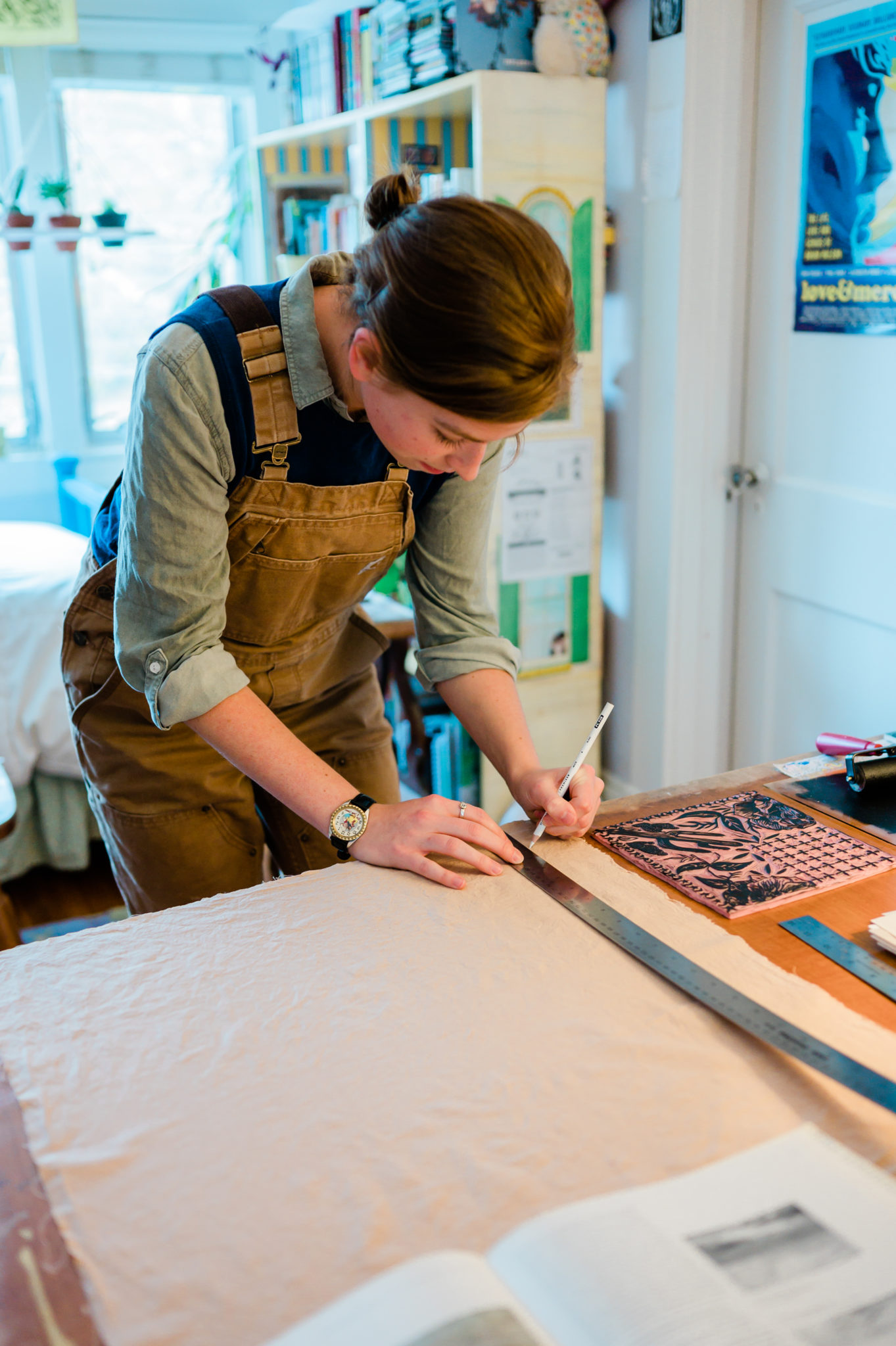 Annabella Boatwright leans over her artist's workbench and measure cloth.