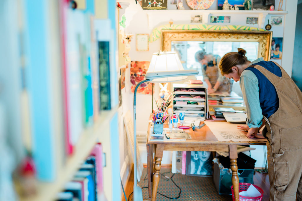 Annabella Boatwright leans over her artist's workbench working.