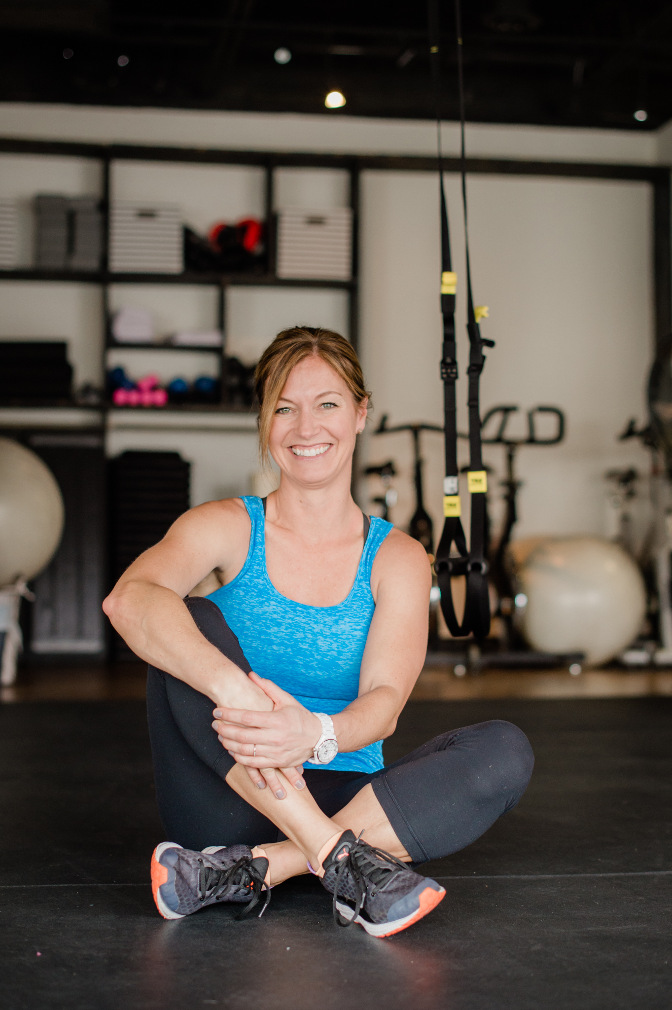 Lori Teppara sits on the floor of FIT HUB smiling.