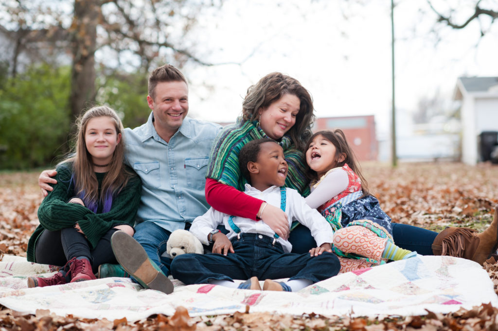 Shane Key sits on a blanket in leaves with his wife, his two daughters, and his son.