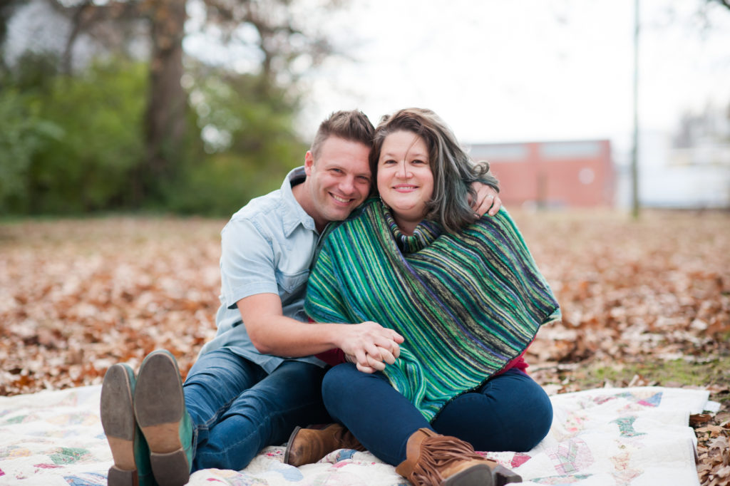 Shane Key and his wife sit on a blanket in the leaves.