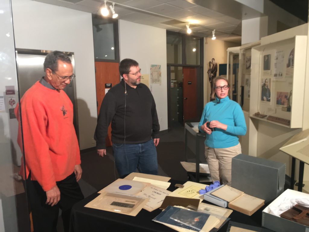 Two men and a woman stand looking at artifacts at High Point Museum.