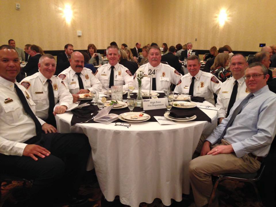 High Point Fire Chief Tommy Reid sits at a banquet table with other fire department staff. He is awarded the 2015 Volunteer of the Year at a Chamber event in February 2016.