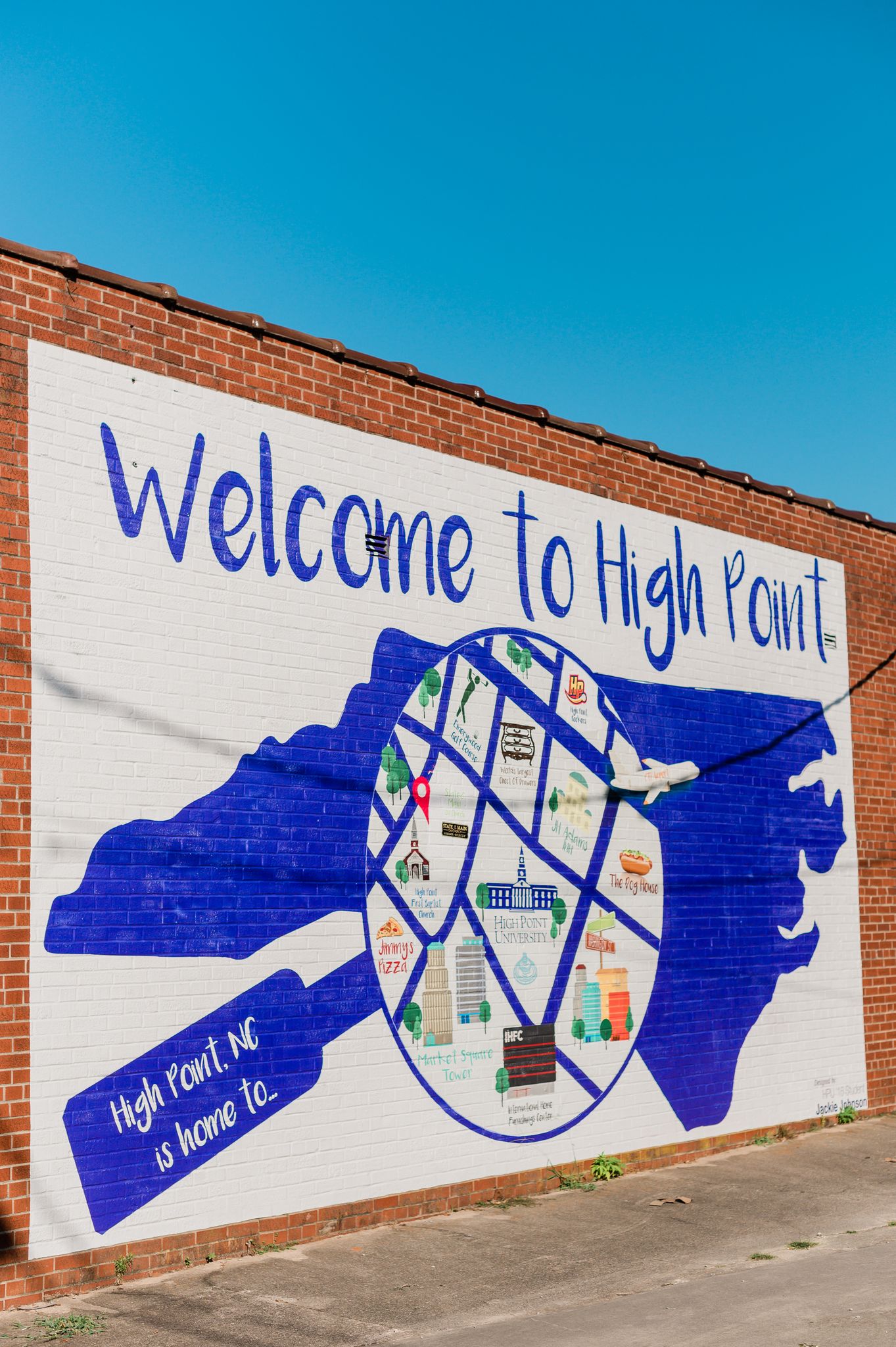 A mural that says "Welcome to High Point." A purple shape of North Carolina has a circle painted over it with specific locations to High Point. 