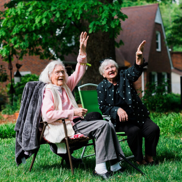 Jean and her daughter sit on the lawn and waving at passing cars as Jean celebrates her 101st birthday.