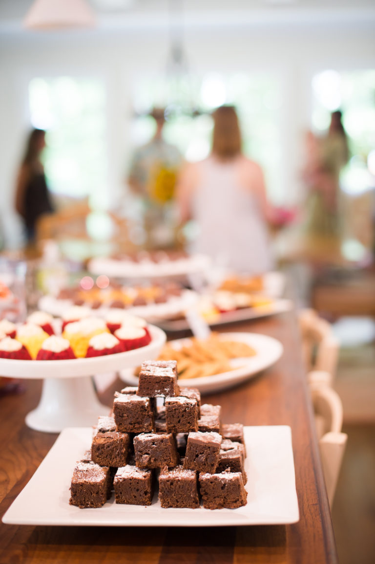 Plate of brownies sits on a table with people in the background.