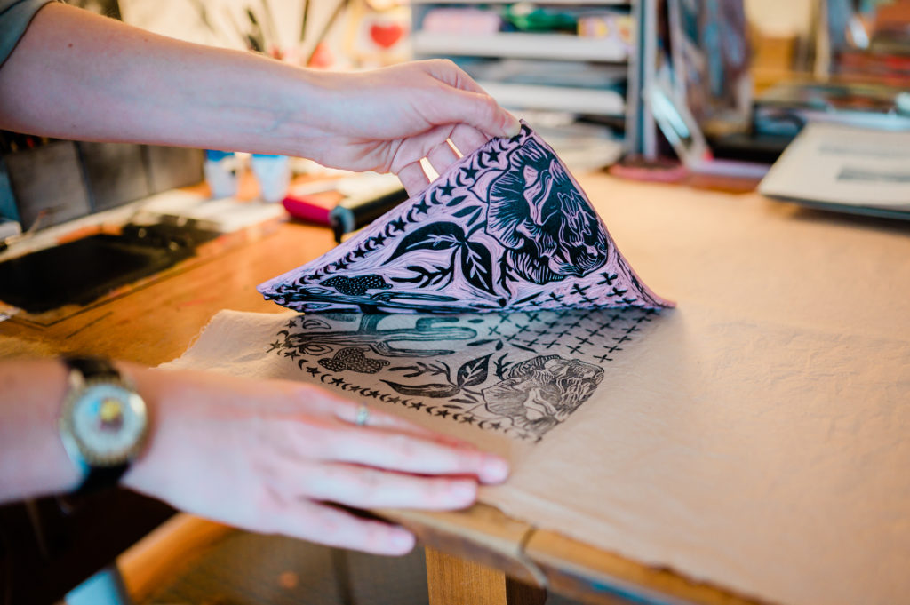A pair of hands pull up a bandana screen printing.