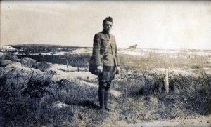 An antique photo of a man standing in a war uniform.