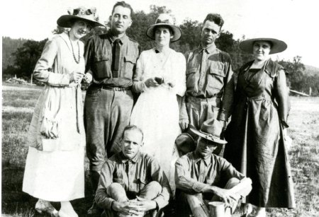 An antique photo of a group of people, the men wearing war uniforms.
