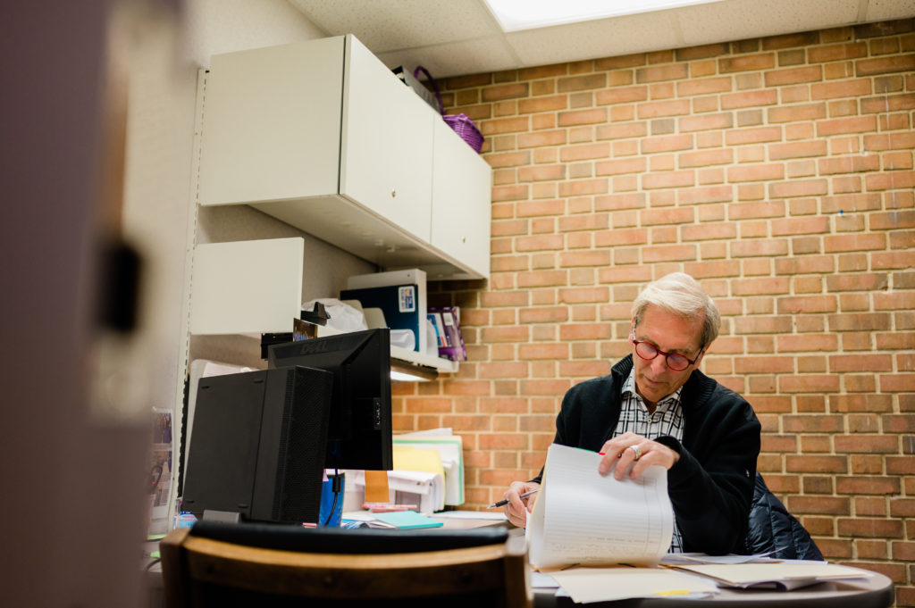 Dr. Frosty Culp, Retired High Point Dentist and volunteer at CCHP sits at his desk filling out paperwork.