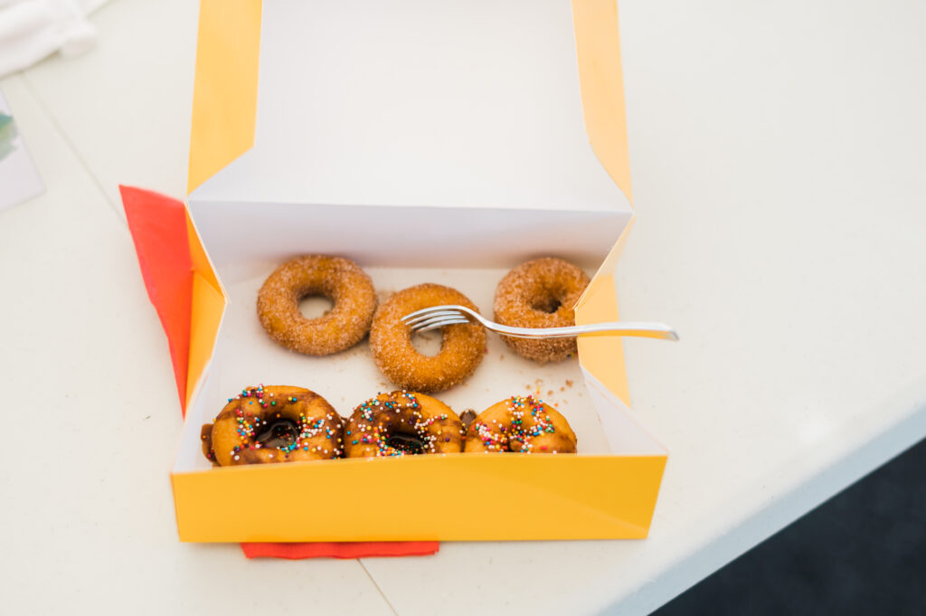 Box of small doughnuts in a yellow box.