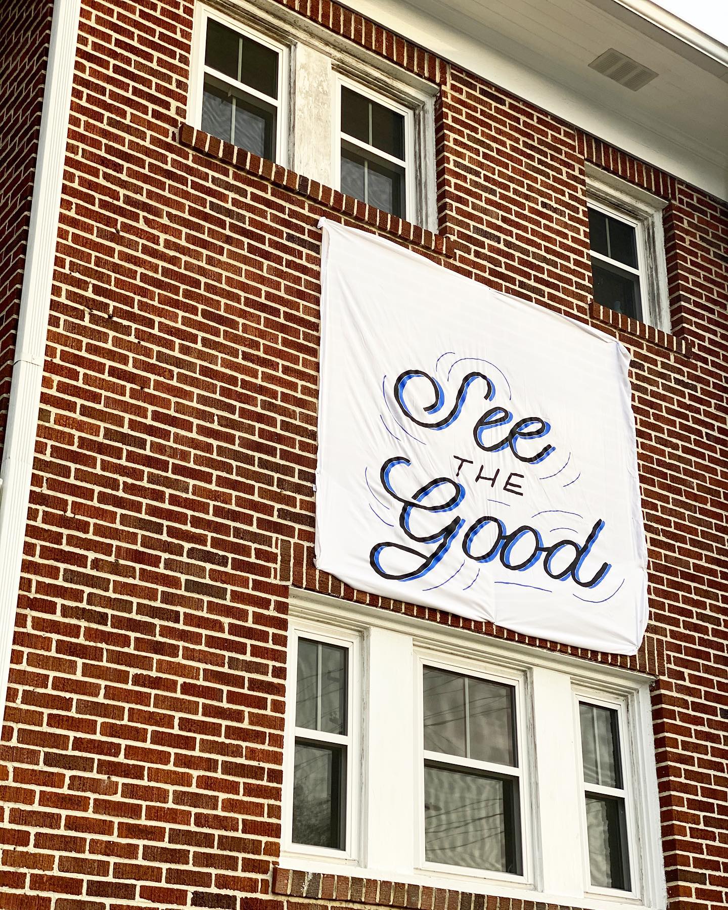 Close up of the sheet that says "See the Good," hanging on The Barbour Spangle Design building.