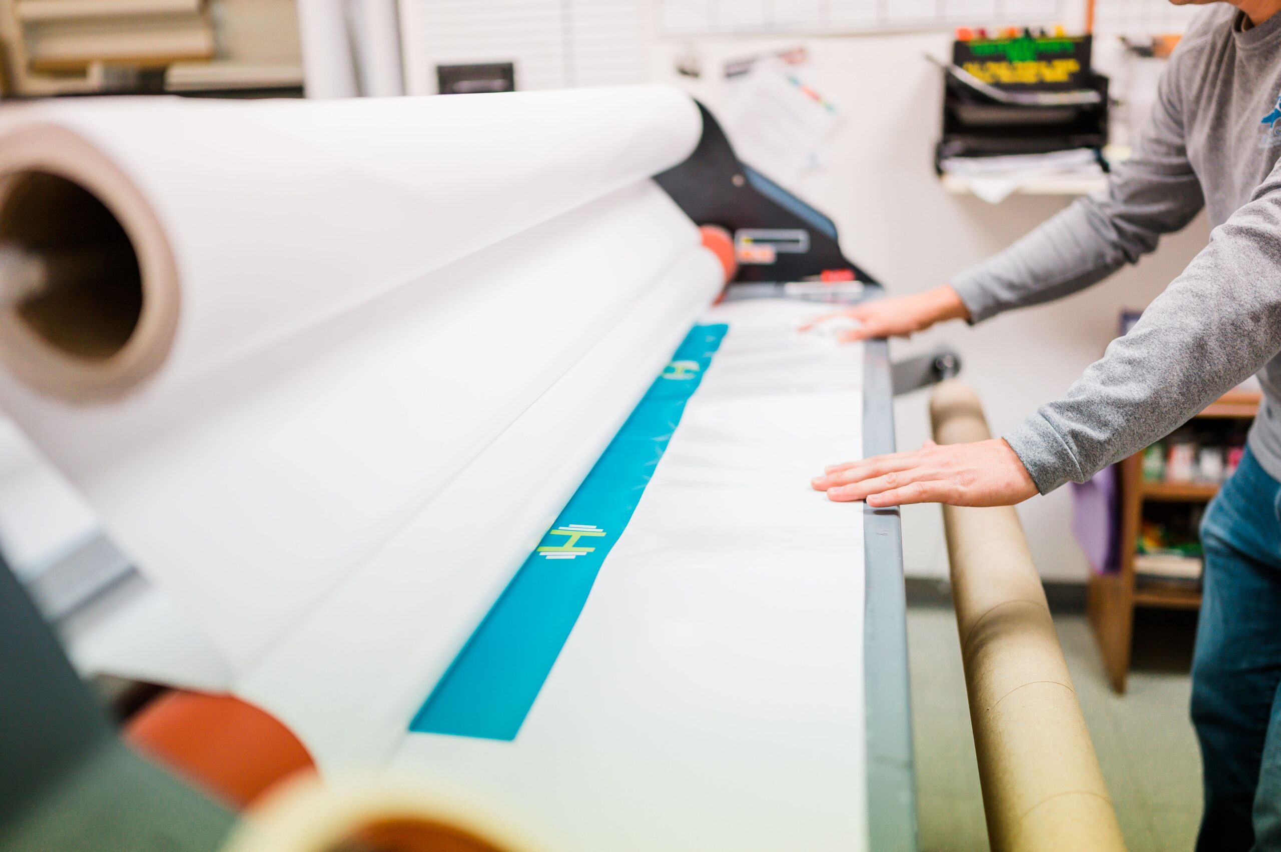 A pair of hands stretches white paper over long drafting table,