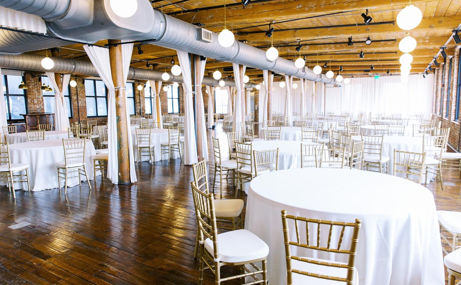 Interior shot of The Lofts at Congdon Yards. White table cloths and banquet chairs sit in a large, open event space. 