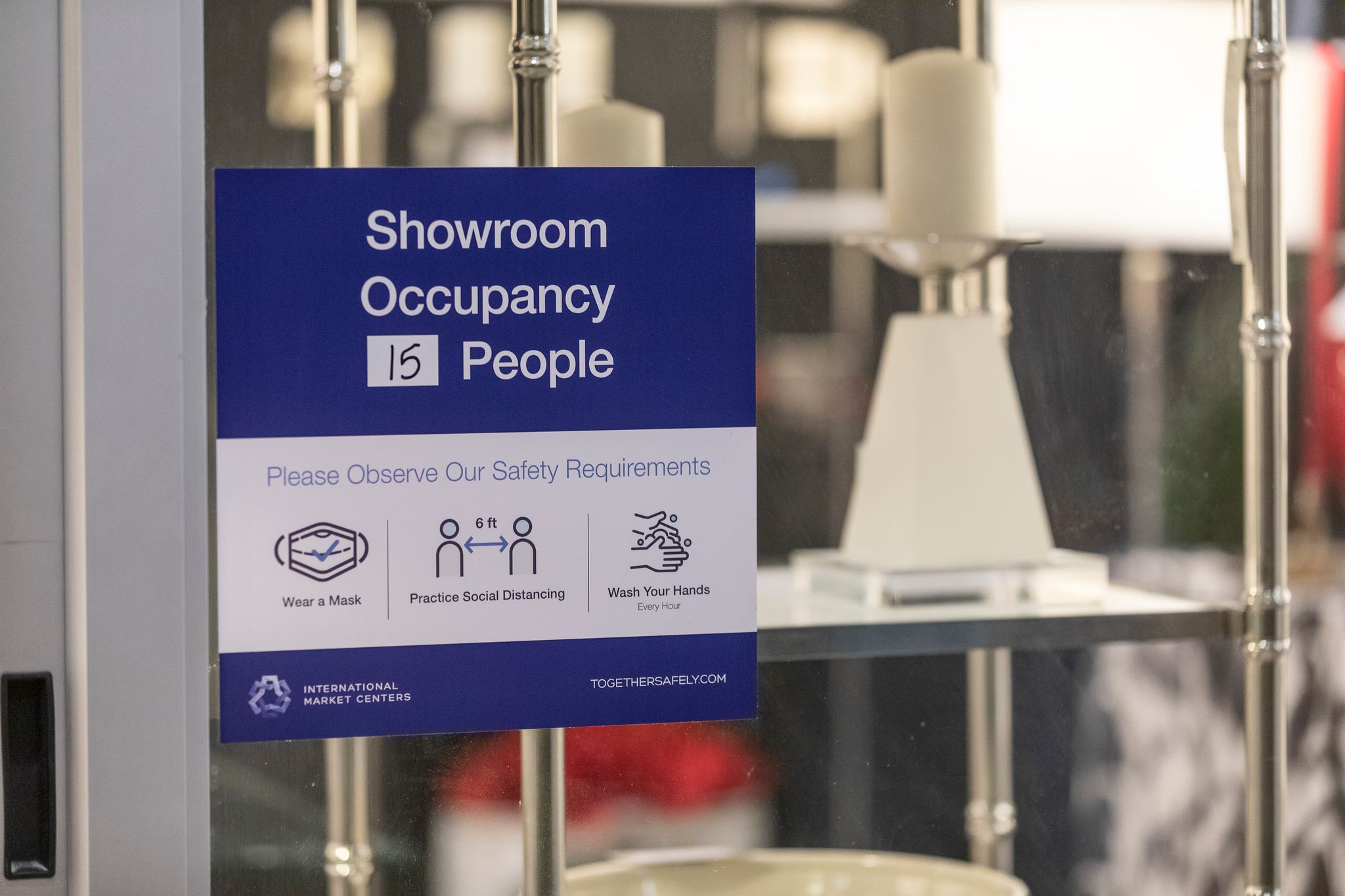 A sign that says "Showroom Occupancy 15 People" hangs on a glass door.