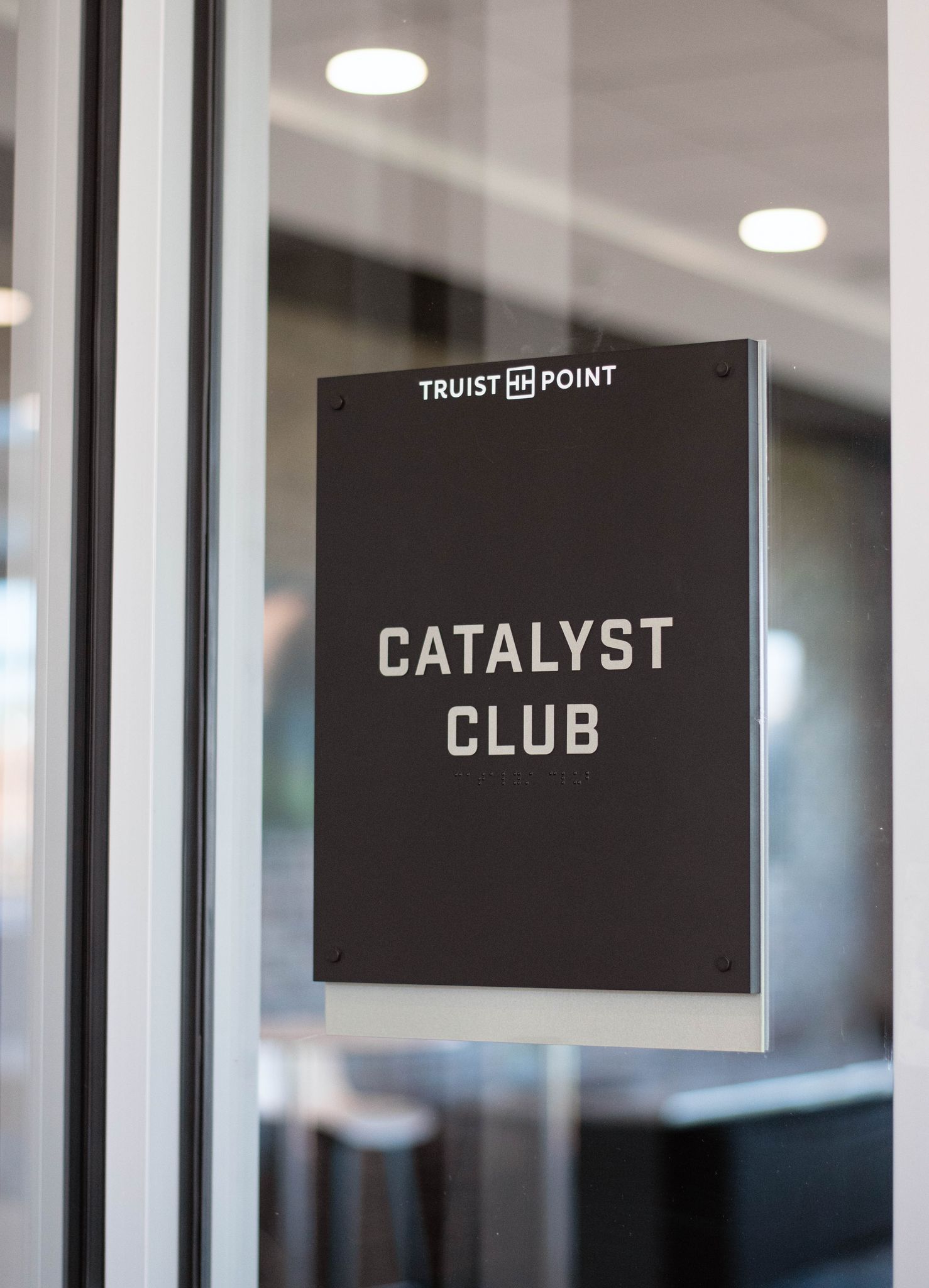A gray sign on a glass door that reads "Catalyst Club."