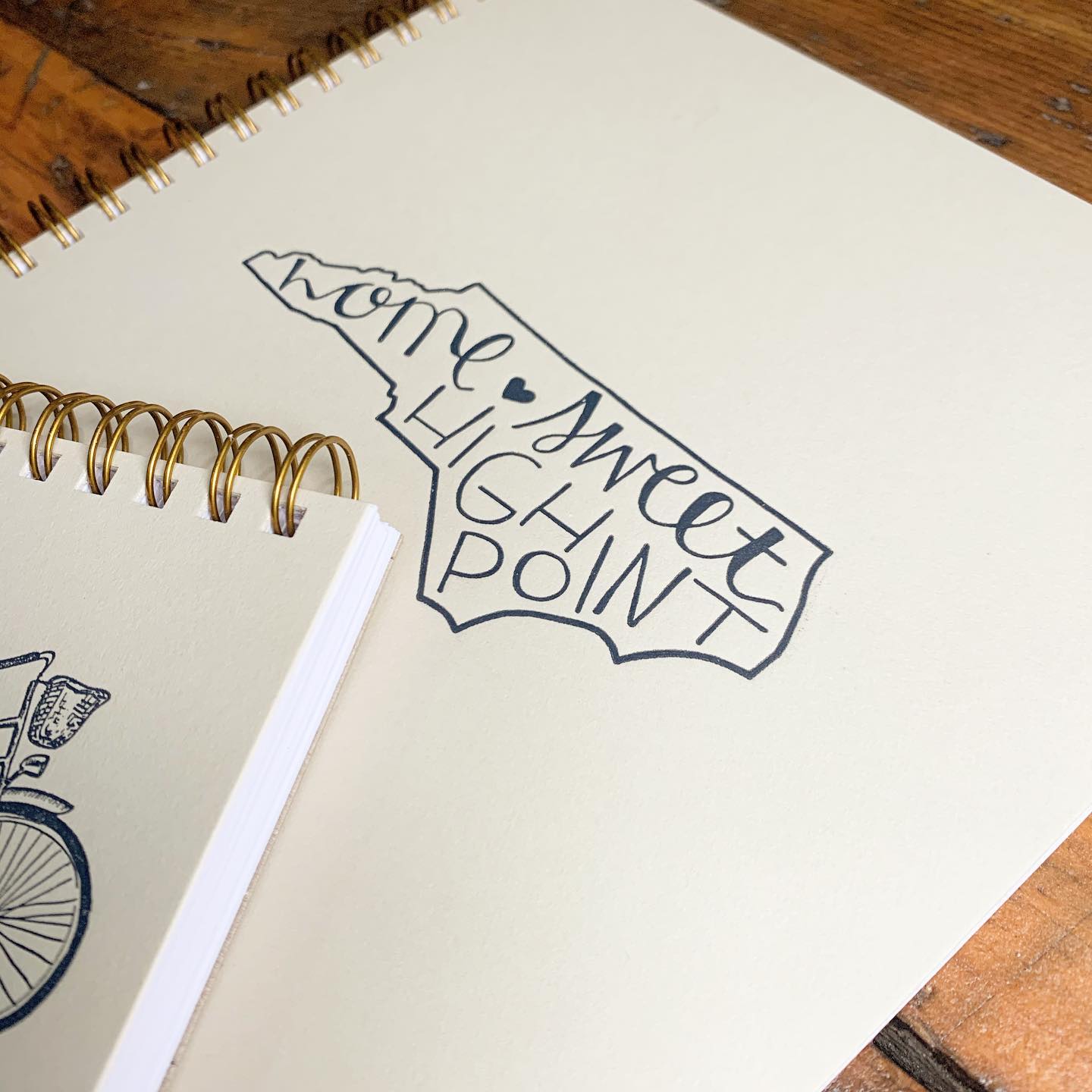 Notebooks with the outline of North Carolina on them that say, "Home Sweet High Point."