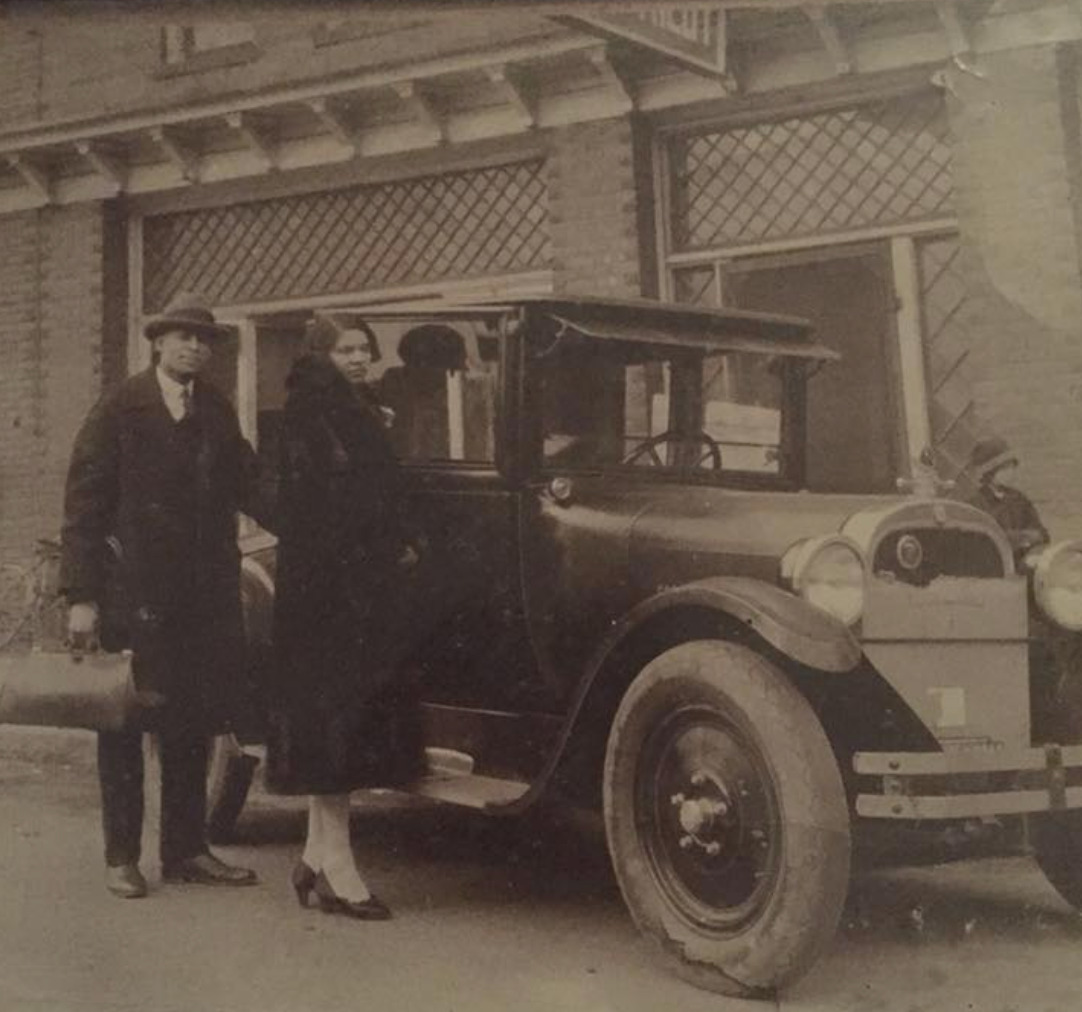 Nannie and John Kilby standing in front of a motor car and the Kilby Hotel in High Point, NC.