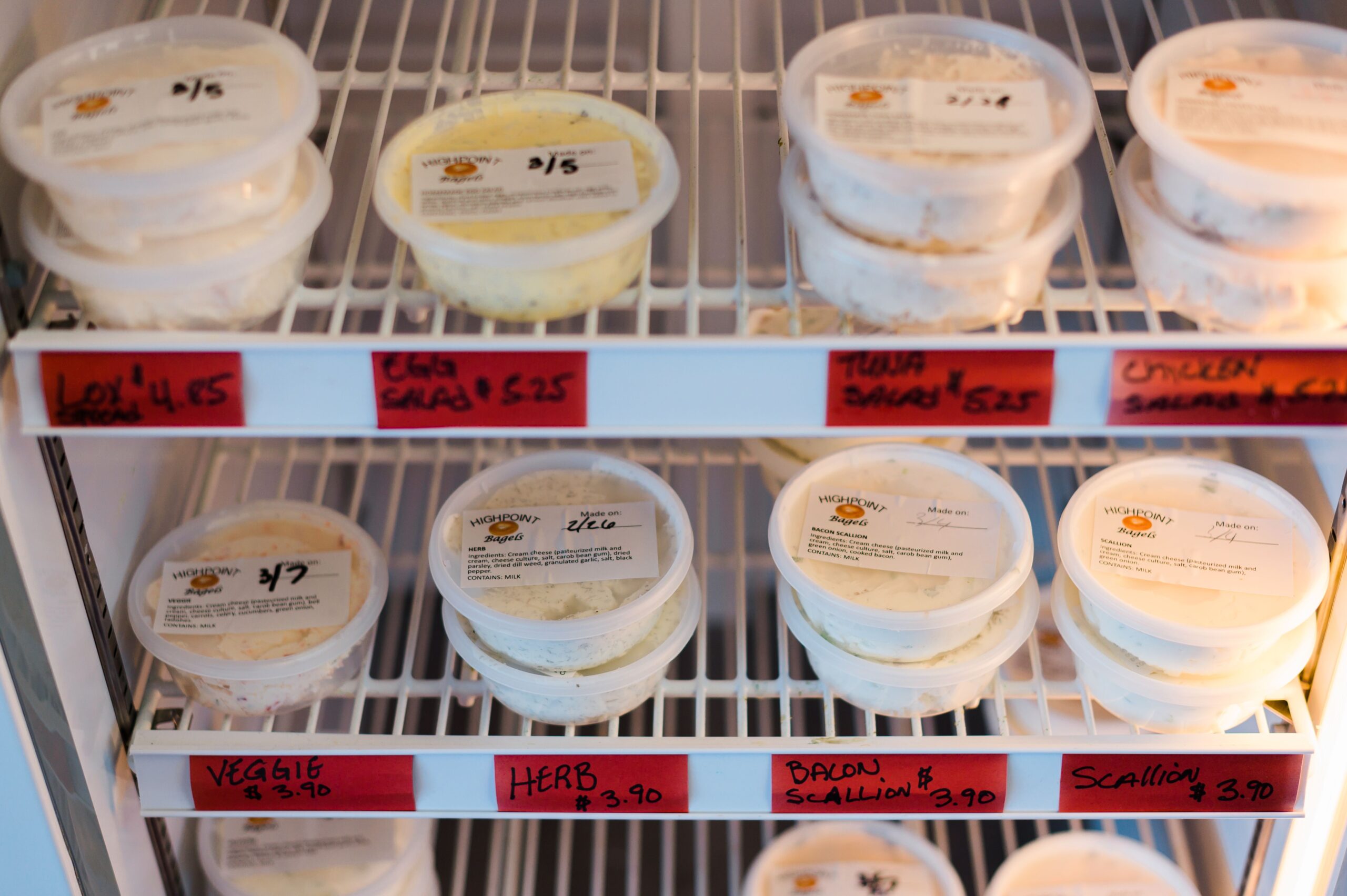 A refrigerator rack of cream cheeses and spreads sits in High Point Bagels in High Point, NC.