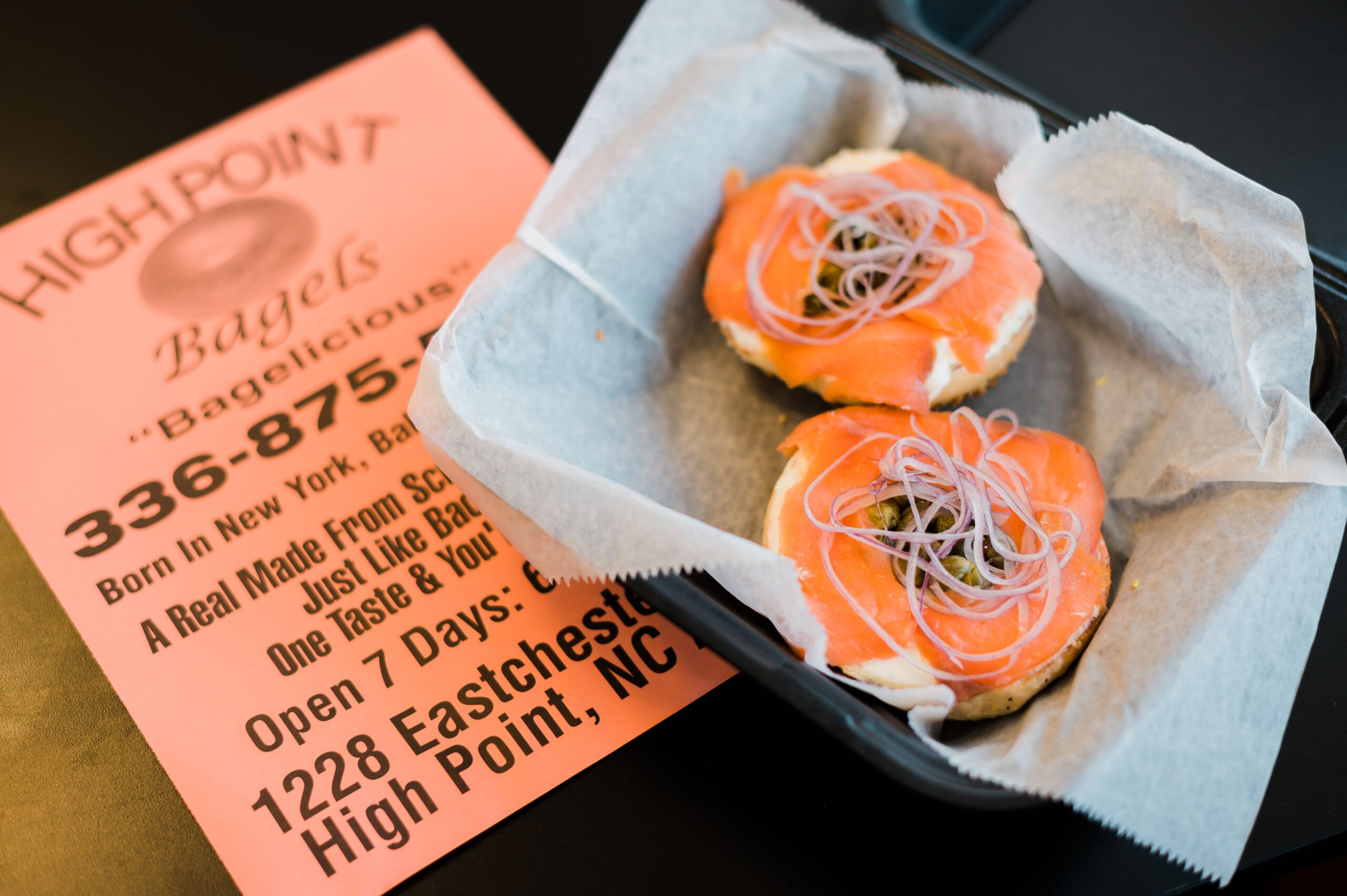 A lox bagel sits in a to-go box at High Point Bagels on top of a menu from the shop in High Point, NC.