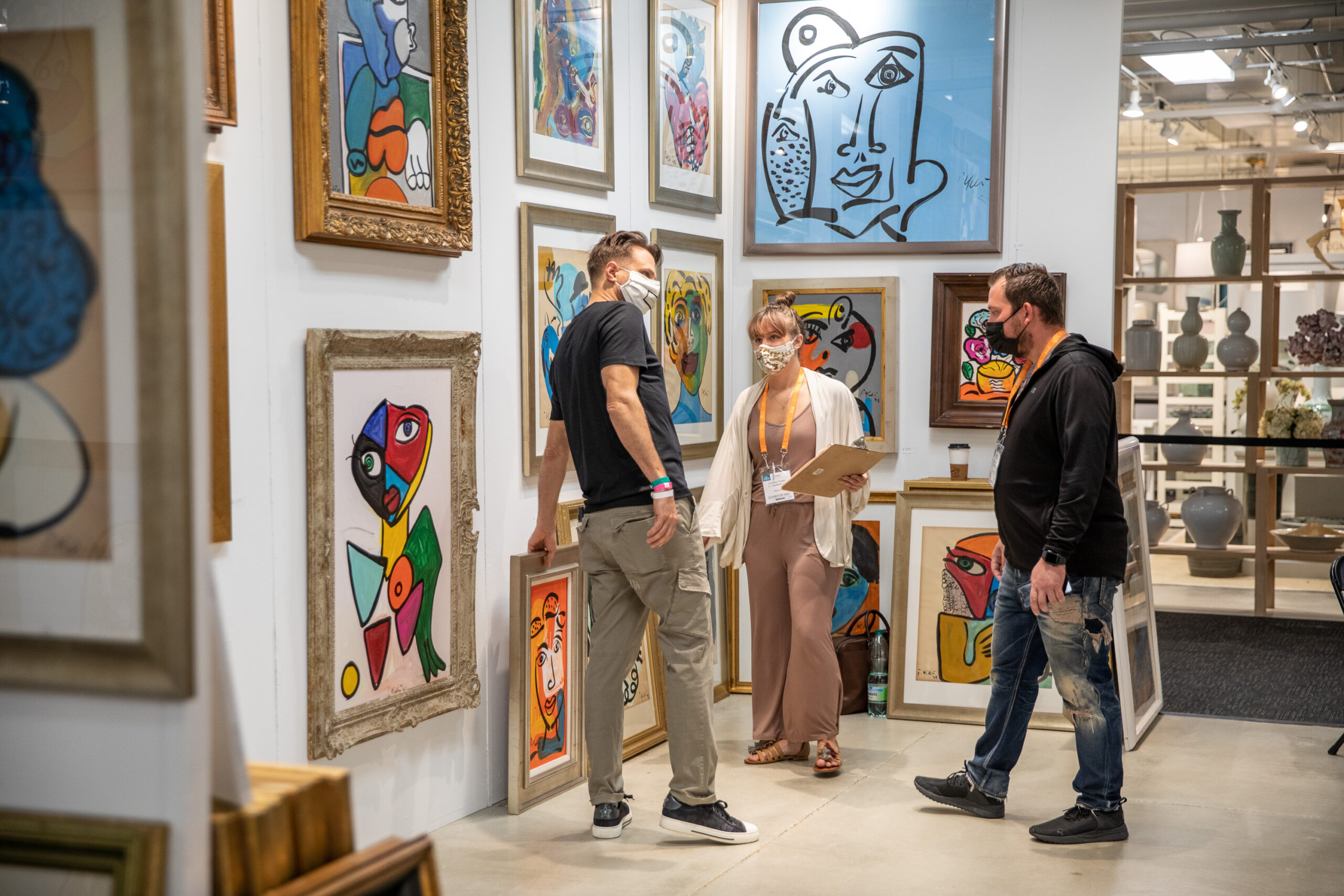 Several people stand together by art work at a furniture showroom in High Point, NC at High Point Market.