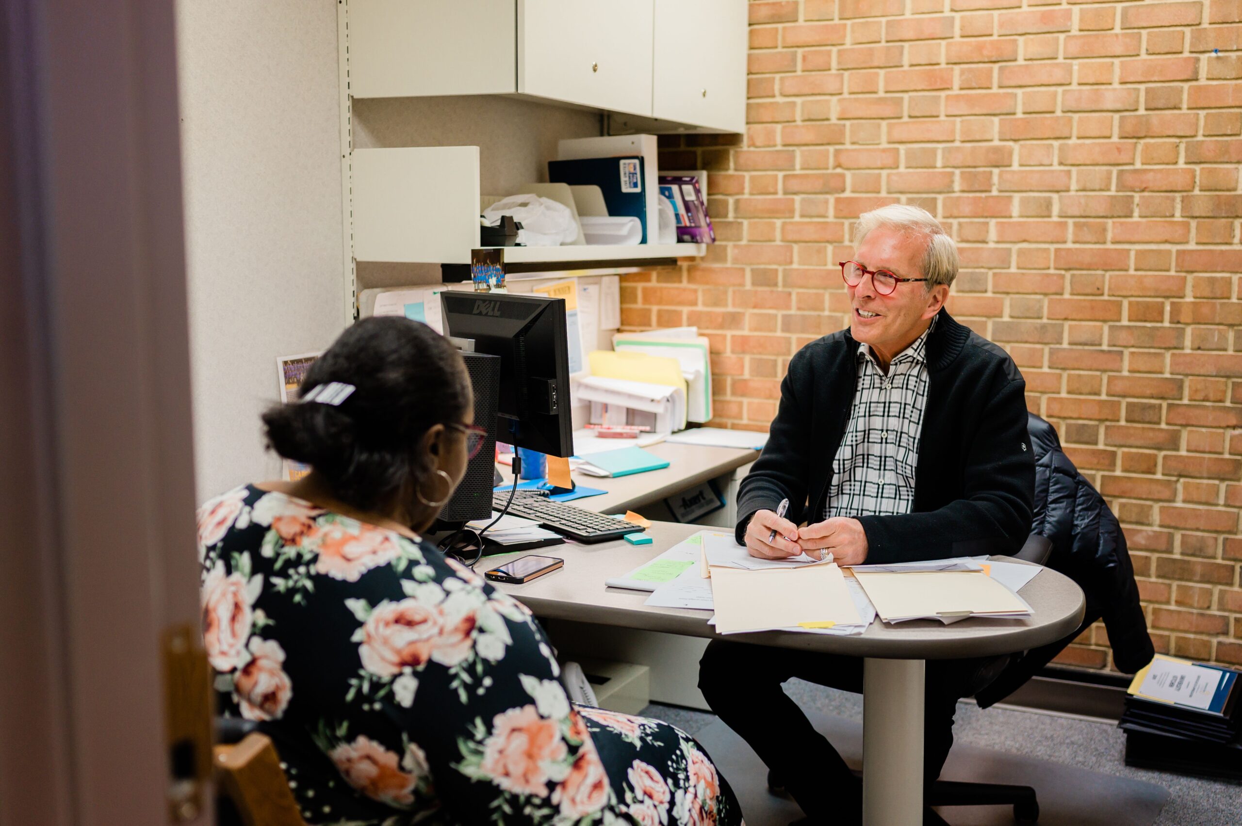 Dr. Frosty Culp sits at a desk, talking to a patient in the Community Clinic of High Point