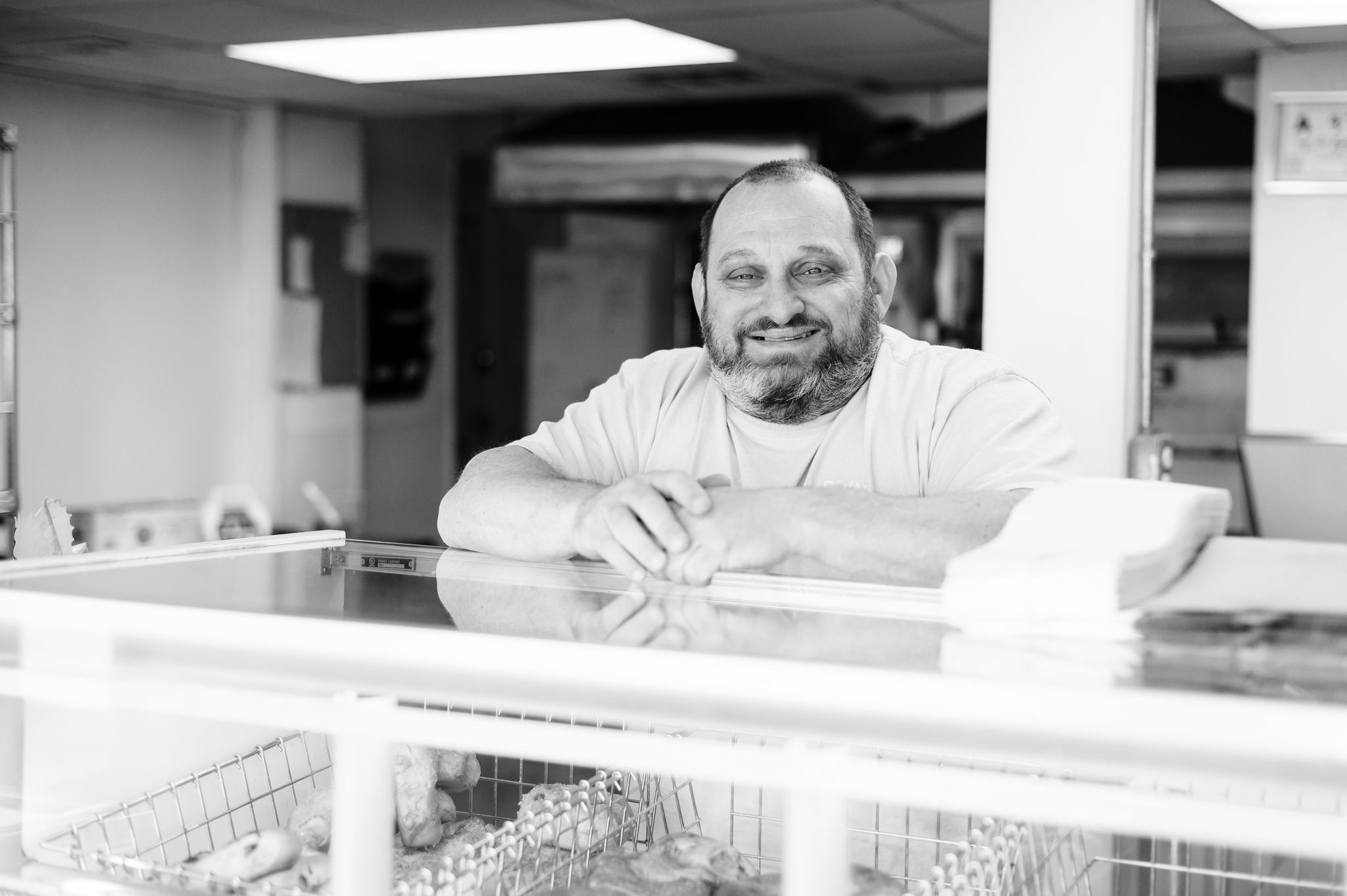 Mat Greenberg, owner of High Point Bagels, smiles standing at the counter of his shop in High Point, NC.