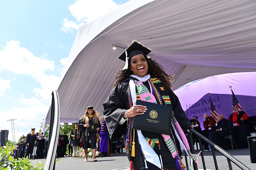 A woman accepts her diploma from High Point University at the 2021 High Point University Commencement.