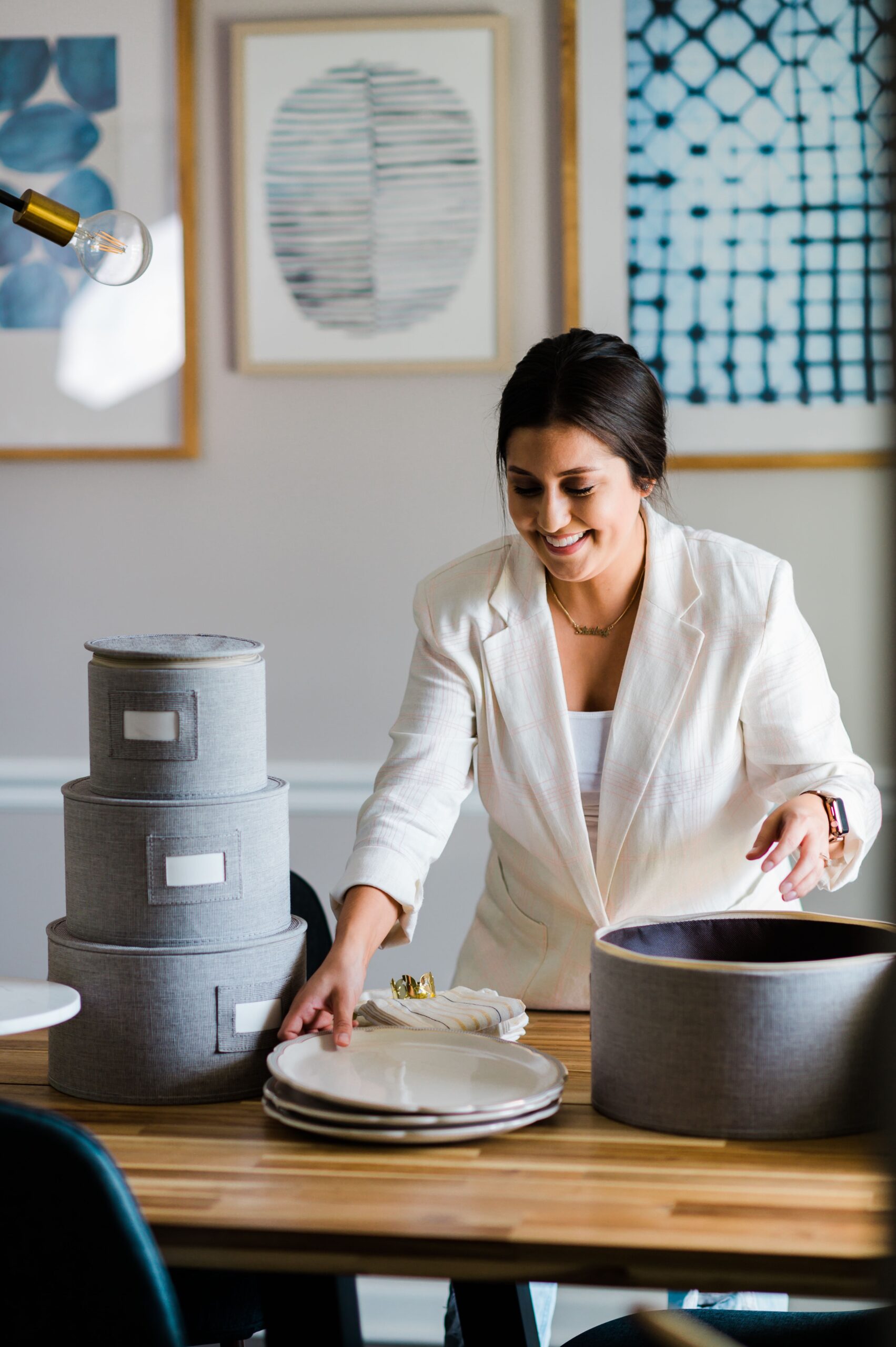 Shirley Simauchi, owner of Homeycasa in High Point, NC, organizes a stack of plates at a table.