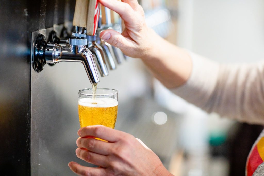 A woman pours a beer from the draft at Goofy Foot Taproom in High Point, NC.