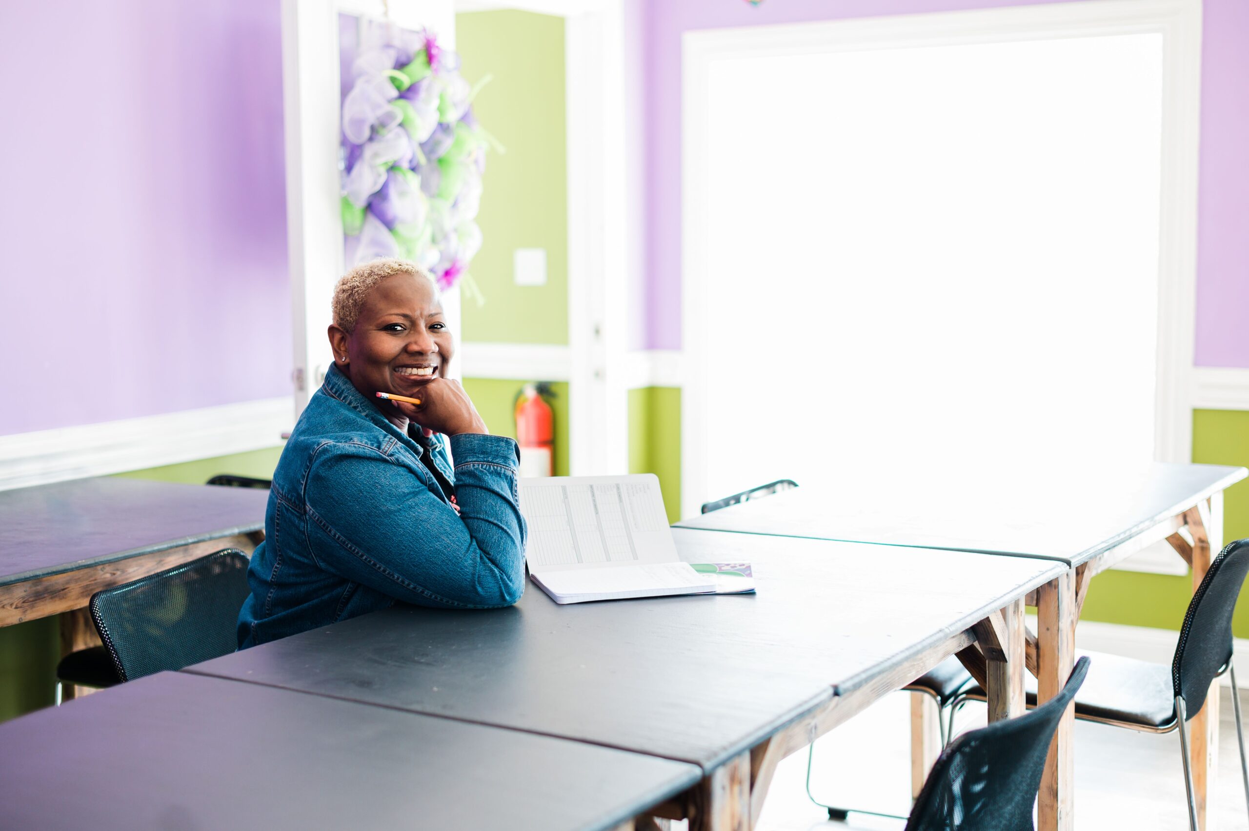 Jakki Davis, executive director and co-founder of D-UP in High Point, NC, sits at a table smiling and taking notes.