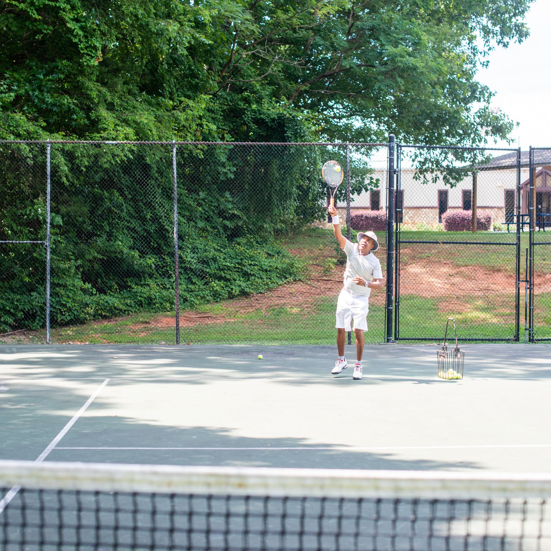 Junius Chatman, Tennis Director at the Oak Hollow Tennis Center in High Point, NC, serves a ball.