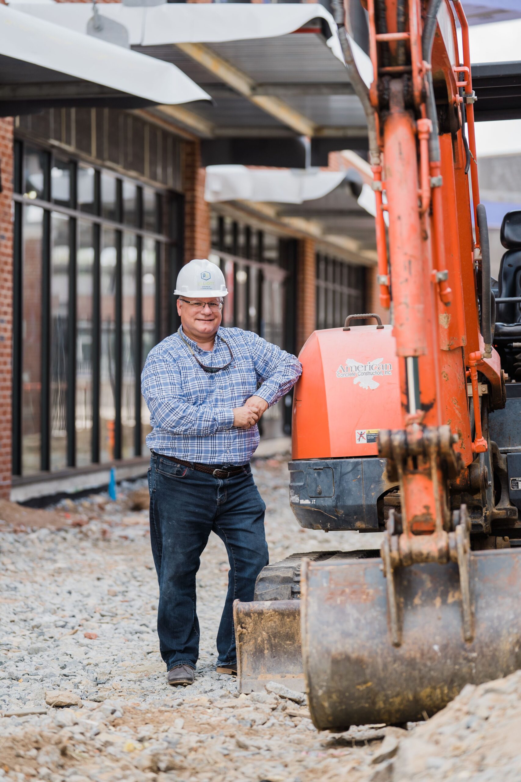 Tim Elliot, Founder of Elliot Sidewalk Communities leans on a bulldozer at High Point, NC.