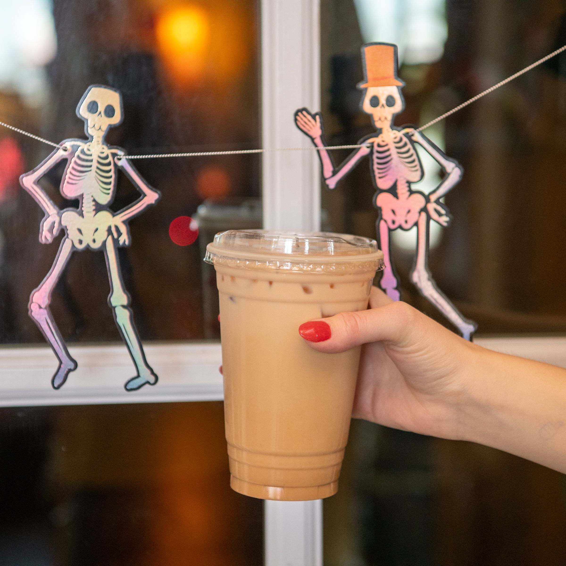 A coffee at DeBeen Espresso in front of halloween dancing skeleton decorations.