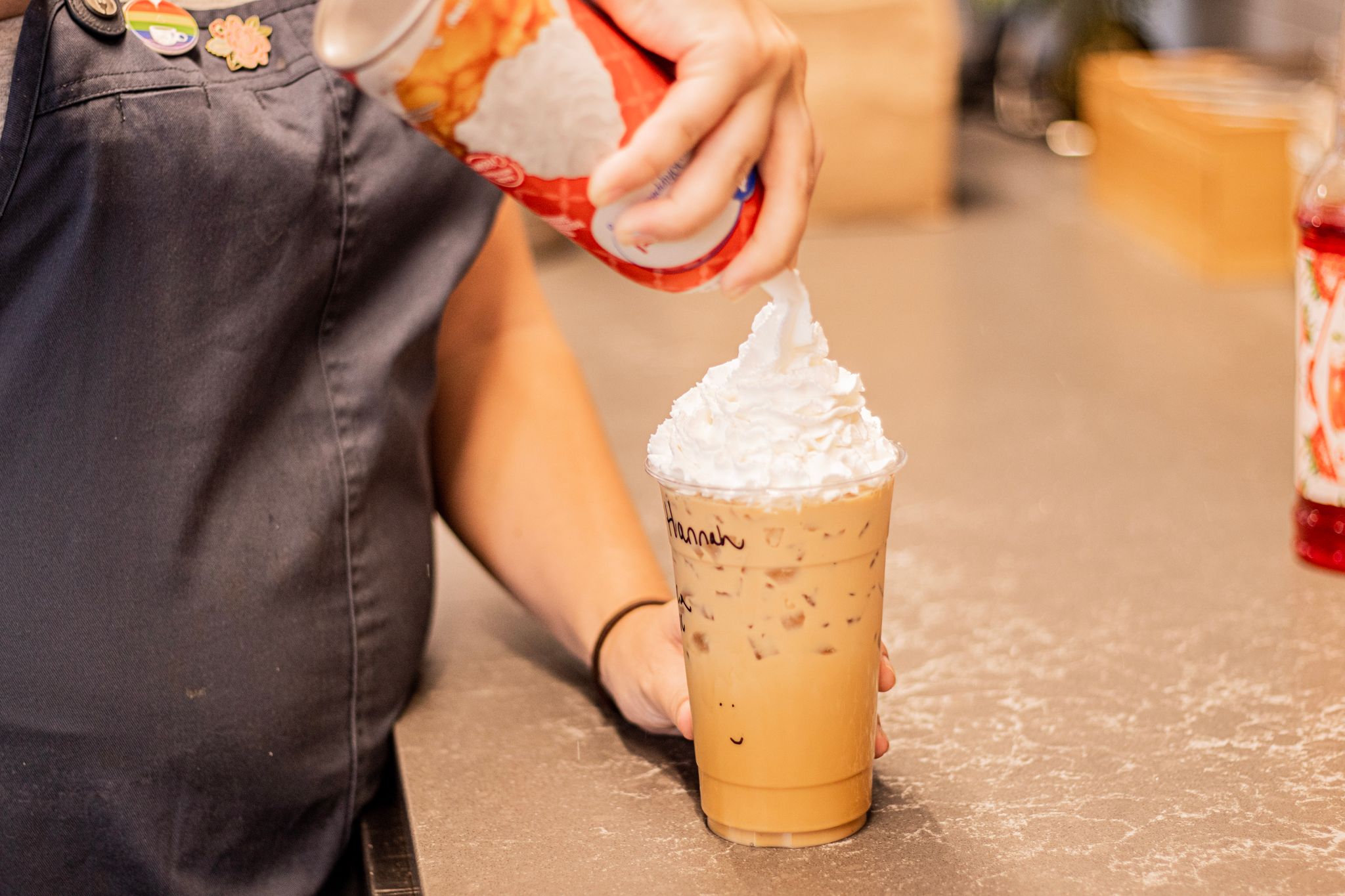 A barista at Lil's Coffee Bar puts whip cream on a coffee.