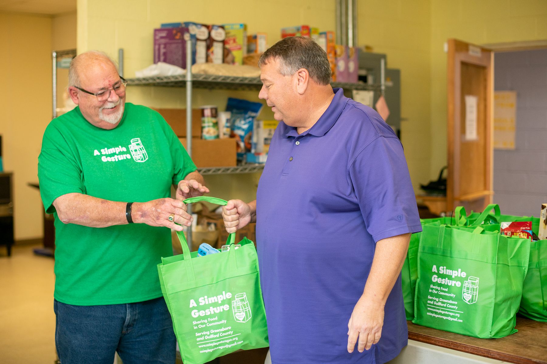 David Lees hands a grocery bag of food to Brad Bowers, Executive Director at A Simple Gesture.