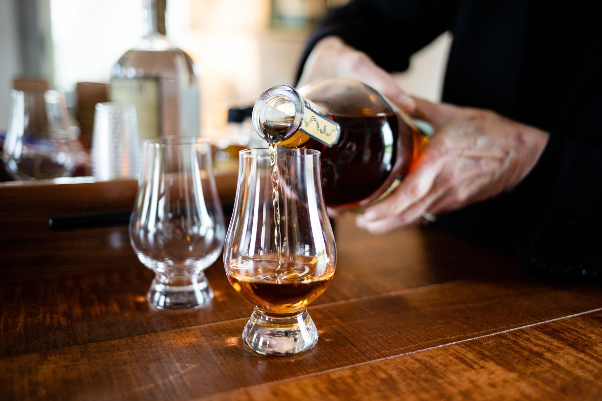 A woman pours Cooper's Cut whiskey into a tasting glass at Founding Fathers Distillery.
