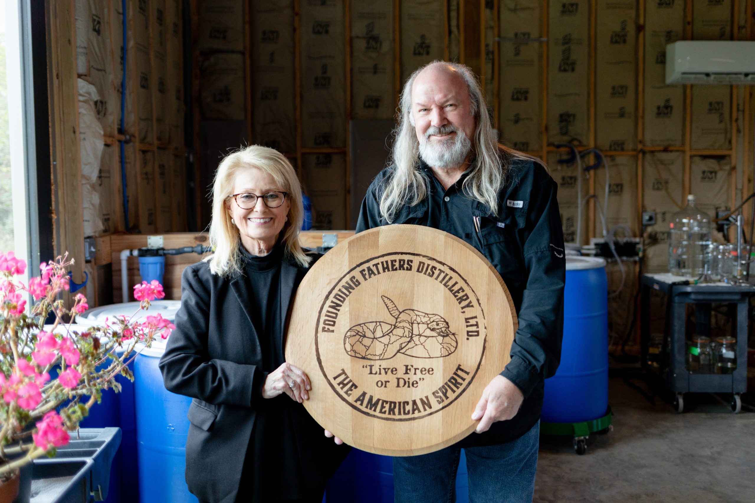 Jeff Cooper and Marta Price, founders of Founding Fathers Distillery in High Point, NC stand with a barrel lid.